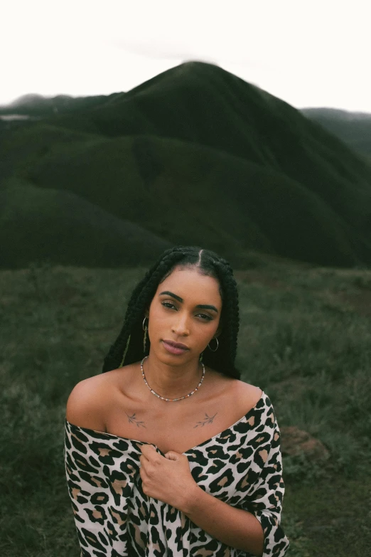 the woman in leopard is posing in front of a mountain