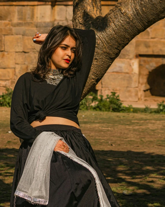 a young woman is leaning against the trunk of a tree