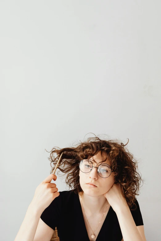 the woman is brushing her hair and holding a piece of scissors