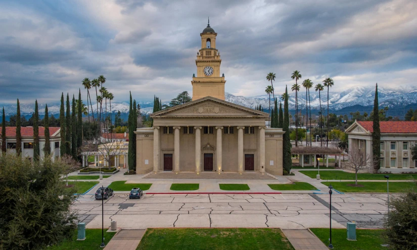 the front entrance to a building with a clock tower and trees in front