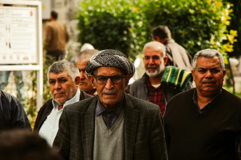 several older men stand with their backs against one another