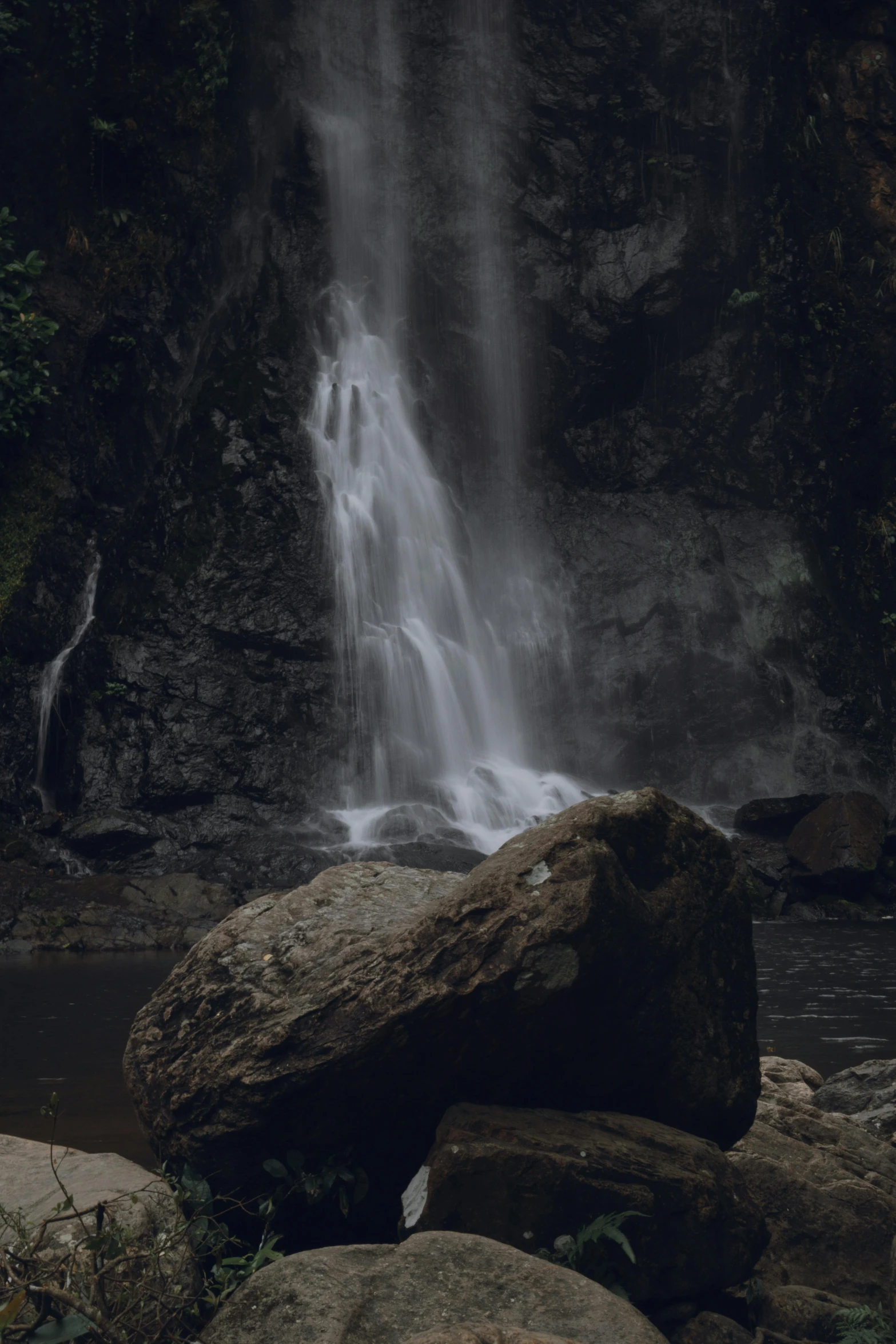 a big rock in front of a waterfall