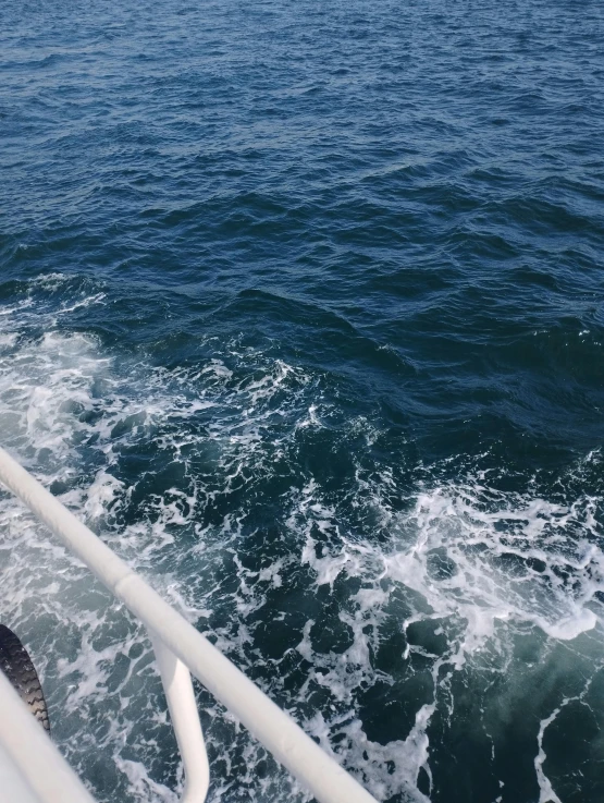 an ocean view with waves coming up from a boat