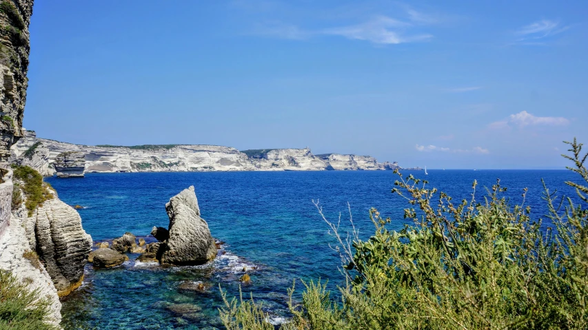 rocks on the edge of a cliff above a blue sea