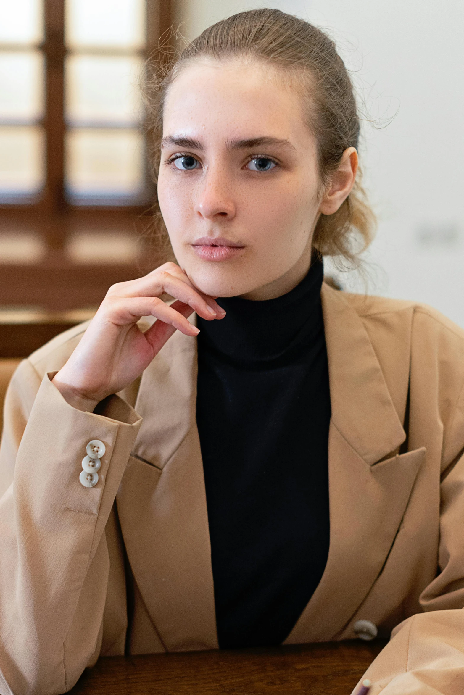 a woman sitting at a desk with her hand on her face