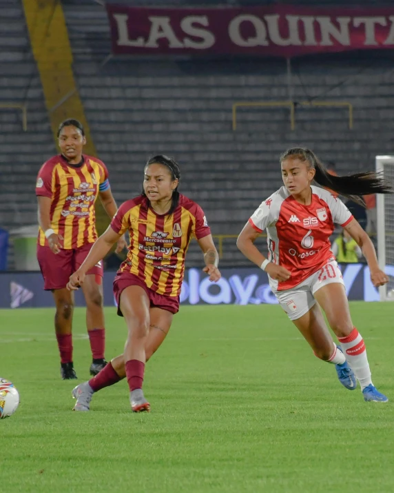 women playing soccer, with spectators in the background