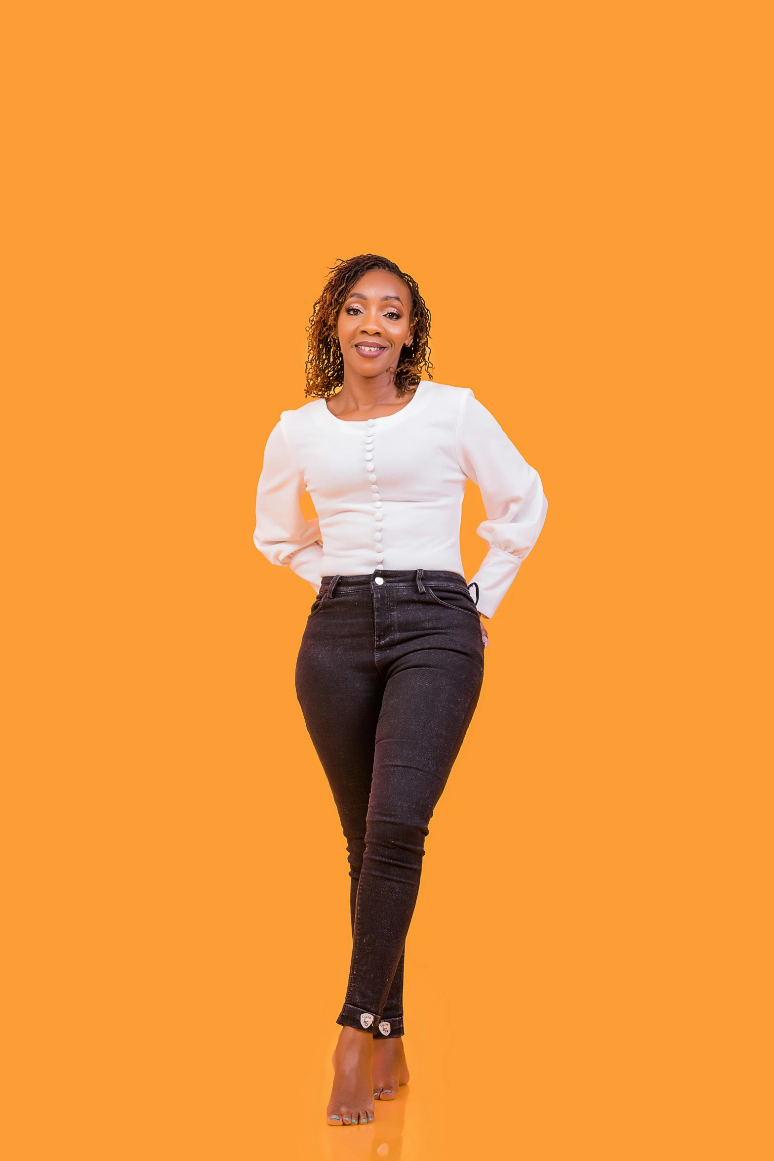 a woman standing in black jeans and white blouse with her hands on hips