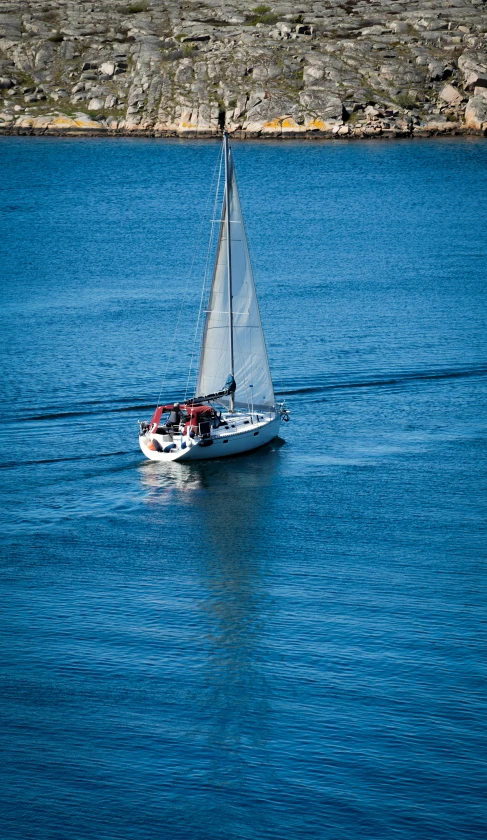 a white sail boat with passengers in a body of water