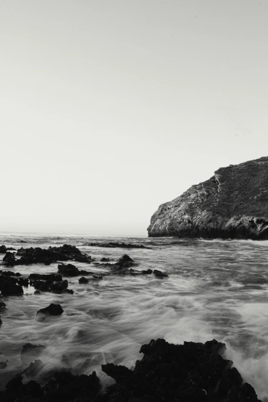 the man is fishing off the rocks at the beach