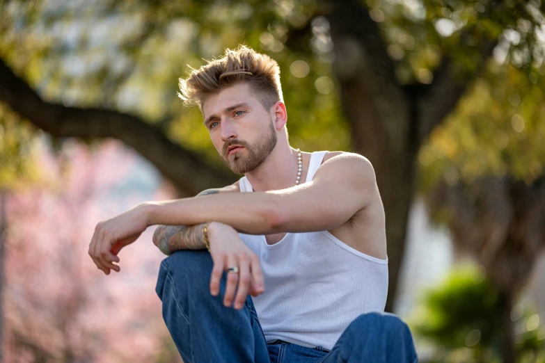 man in tank top sitting on curb outside during daytime