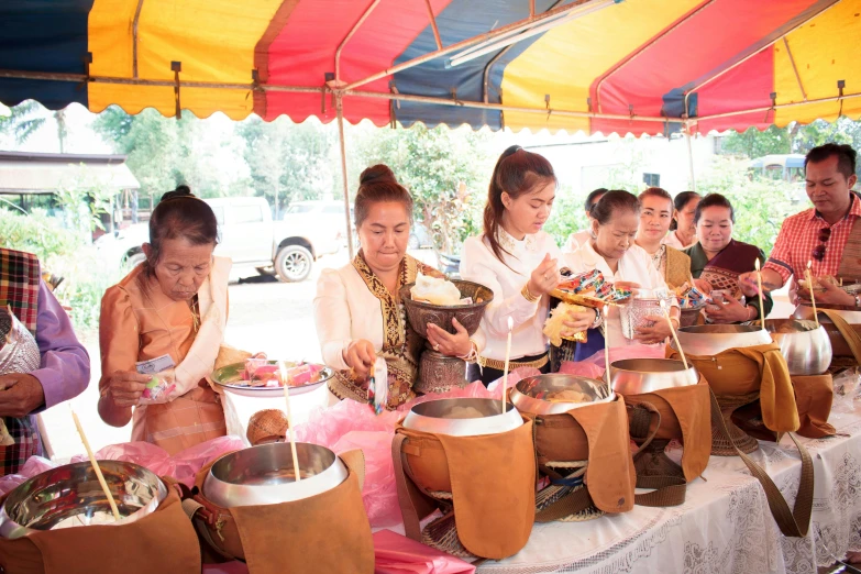 people at a food stall making offerings for the thai gods