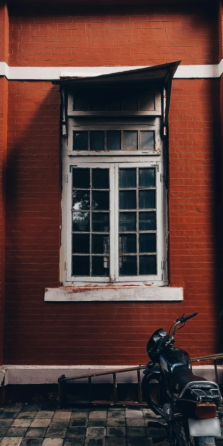 a motor bike and motor scooter parked outside of a brick building