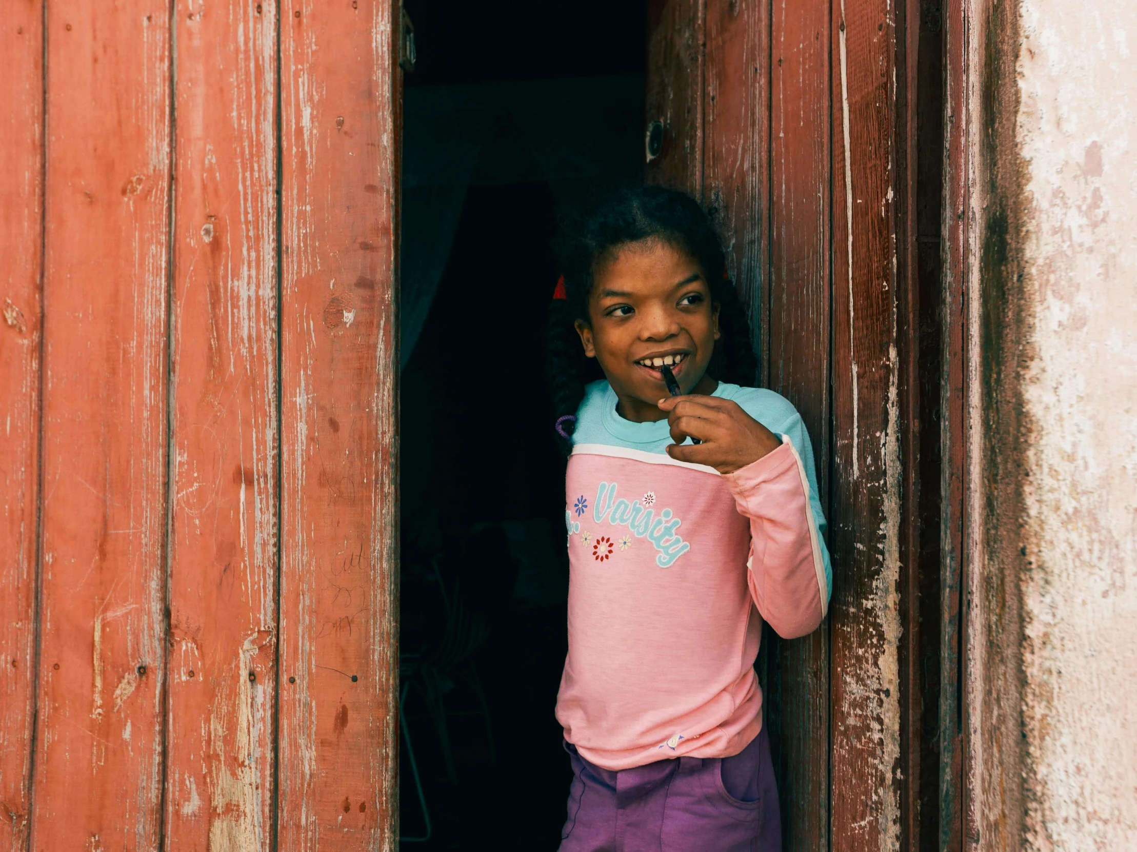 a  brushing her teeth out of an open barn door