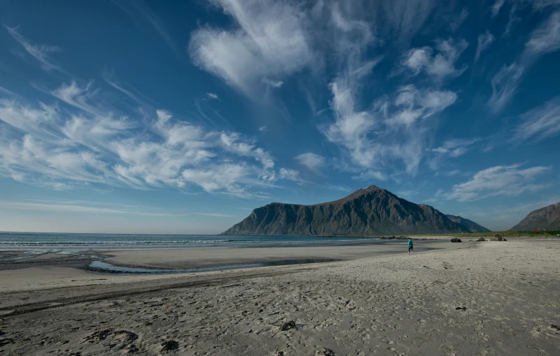 a lone person is standing on the beach looking out to sea