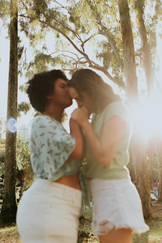 two young women standing in the woods kissing each other