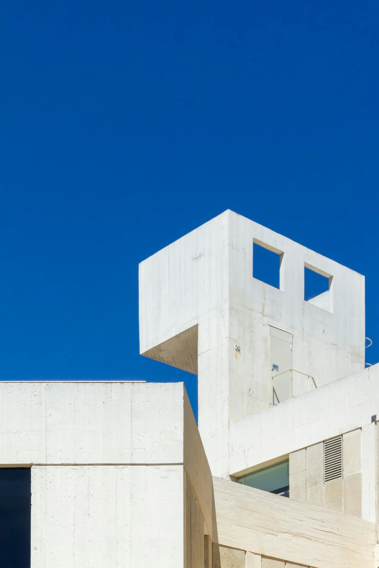 an unusual looking building made from concrete, with windows and a staircase leading up into the sky