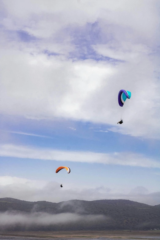 two paraglides gliding on the wind at low altitude