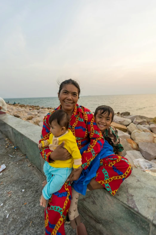 two women with two children posing on a rock wall next to water