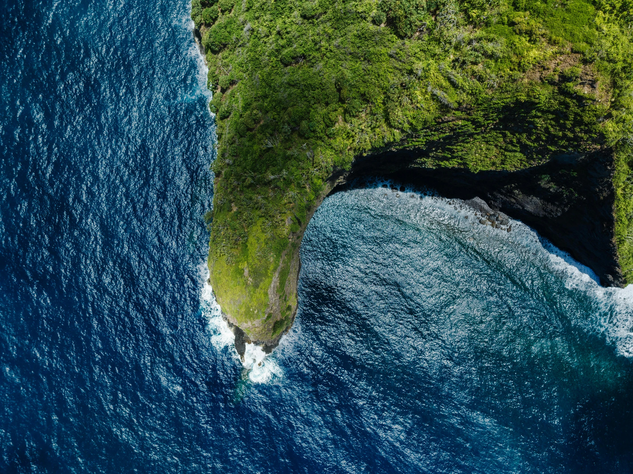 the blue water is next to an island with a large rock at one end