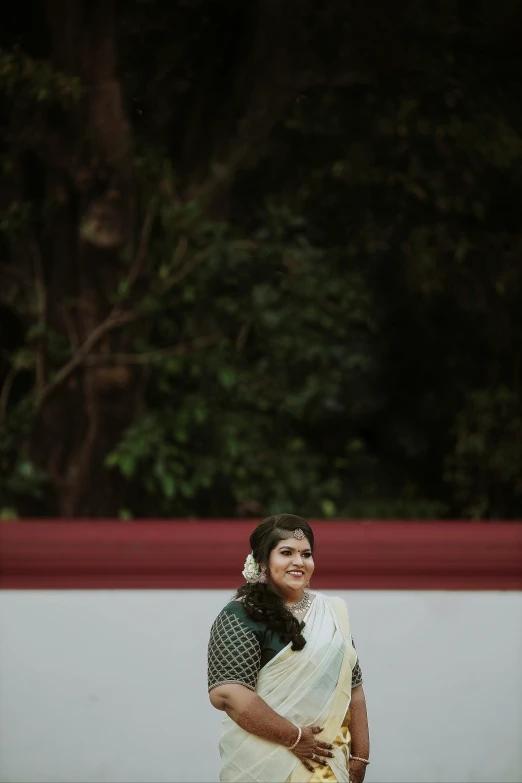 a woman stands in front of a red fence with her head resting on a black umbrella