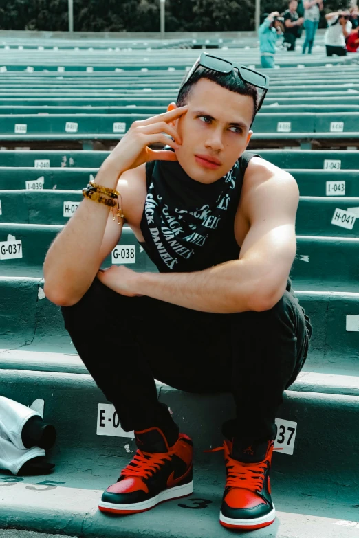 a young man with sunglasses sitting on a stadium bleachers