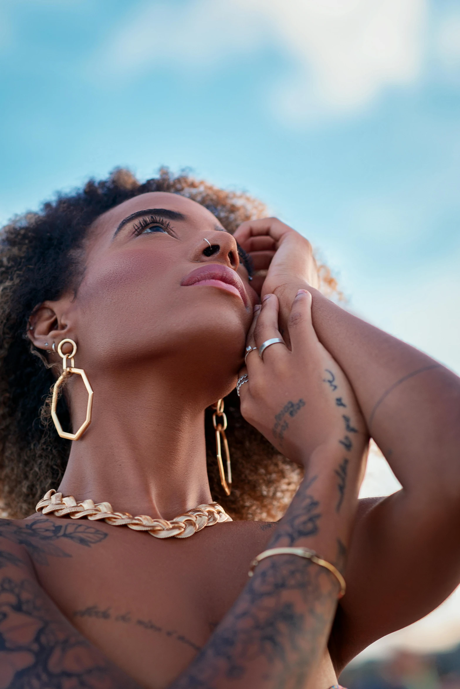 a woman with tattoos on her chest and wearing large hoop earrings