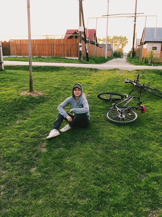 a person sitting in the grass next to an upside down bicycle