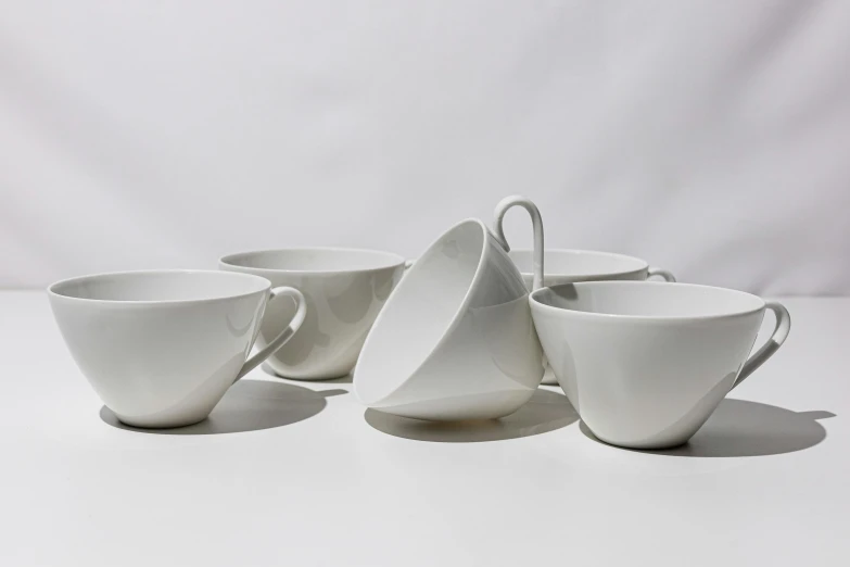 a small group of four white coffee cups and saucers