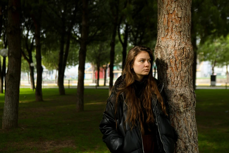 a woman in a park next to a tree