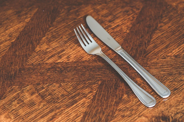 the two silverware are on a wooden table