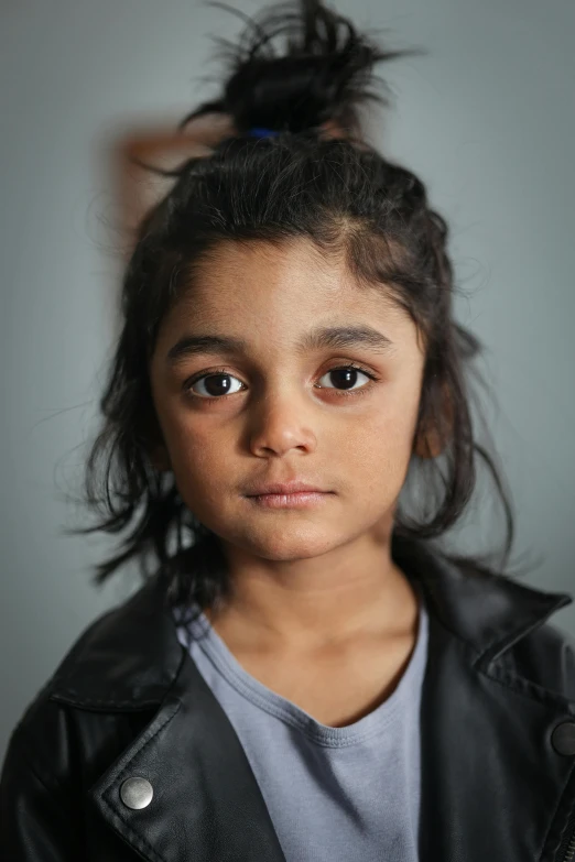 a girl in a leather jacket is staring at the camera