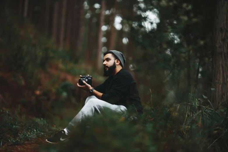 the man is holding a camera in a wooded area