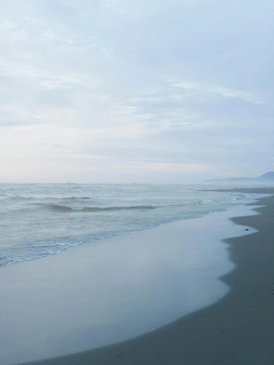 a person walks along the shoreline as it rains