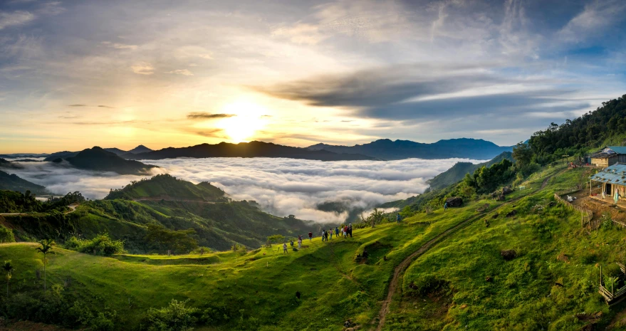 a view of clouds above some green mountains