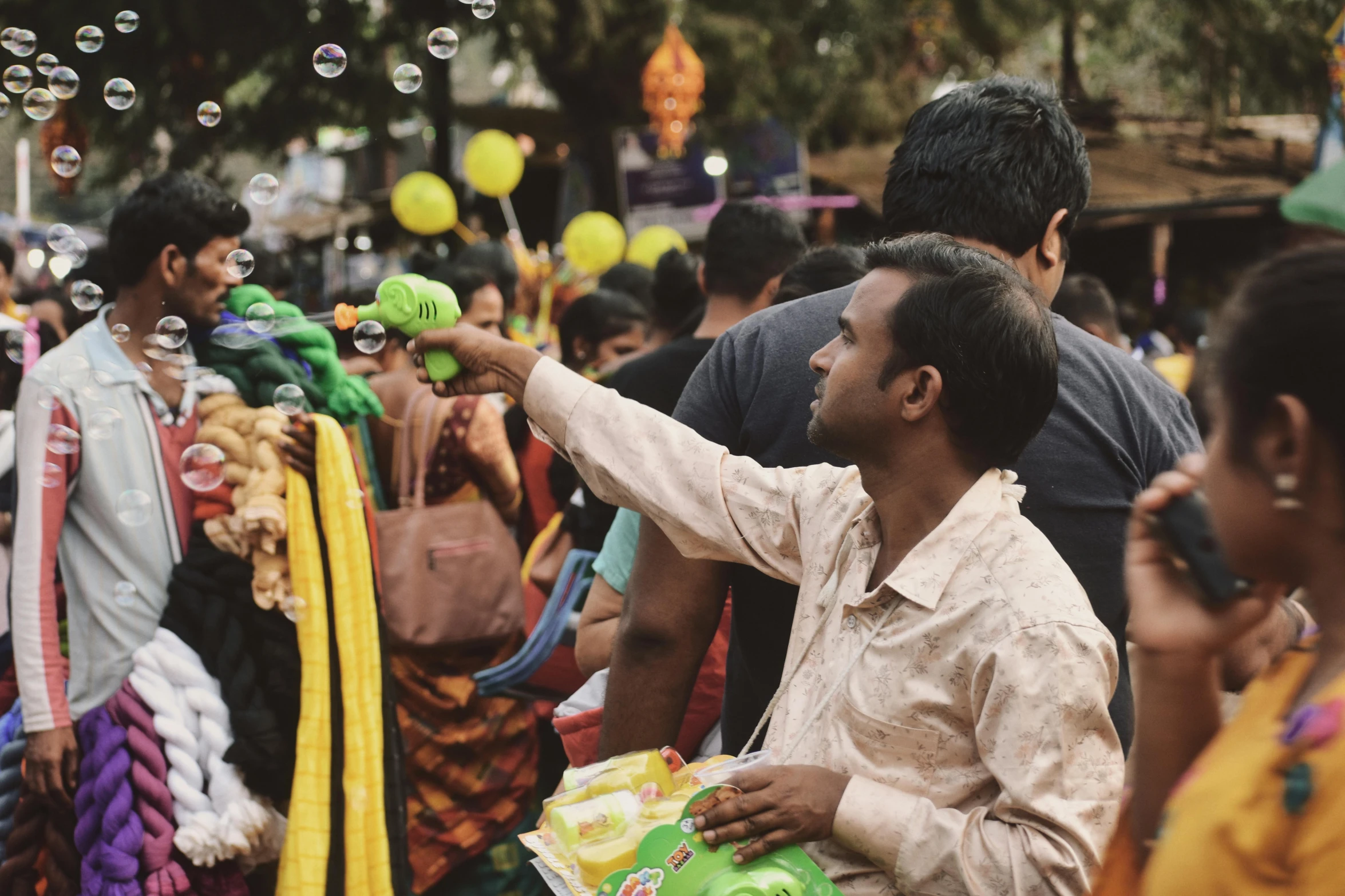 some people bubbles yellow and green balls and a man is pointing