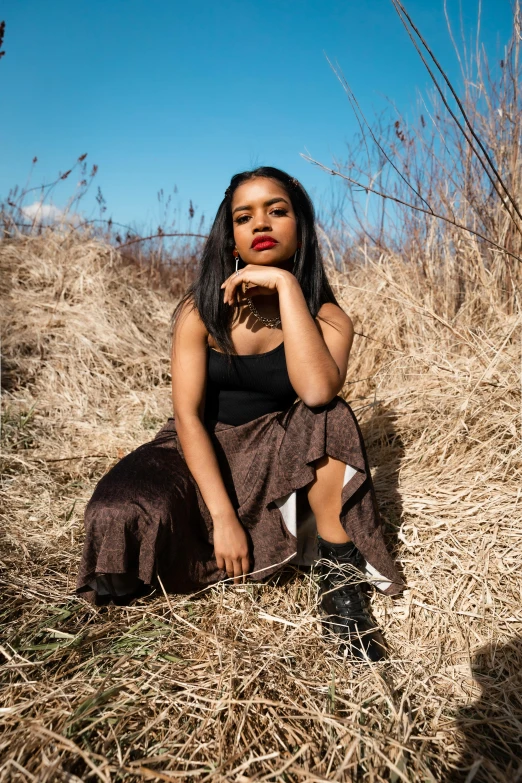 a young woman sitting on the ground with her hands clasped to her mouth