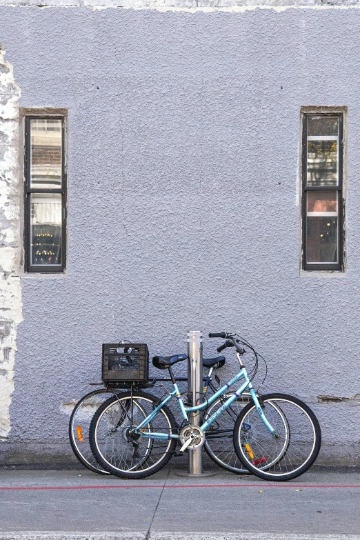 two blue bicycles parked up against a white wall