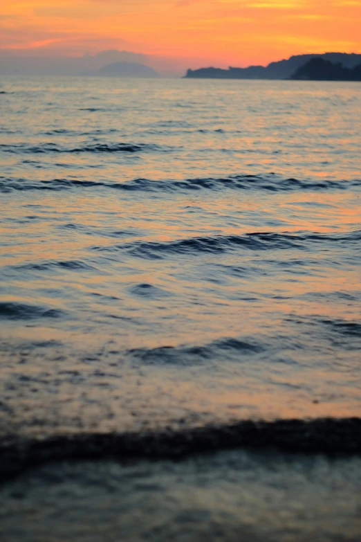 some waves come in to shore at sunset