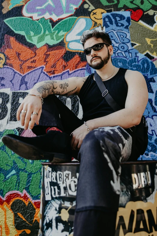 a young man sitting on the bench in front of graffiti