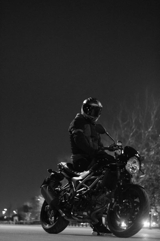 the person is riding his motorcycle in the dark