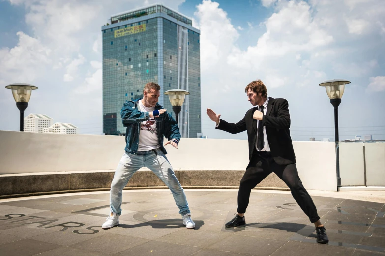 two young men are fighting on a rooftop