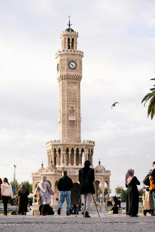 people waiting in front of a very tall clock tower