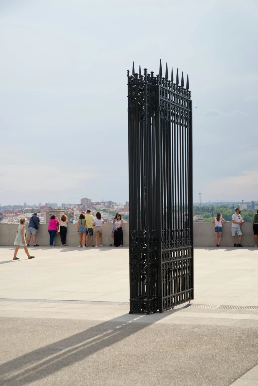 a group of people standing next to a black metal gate