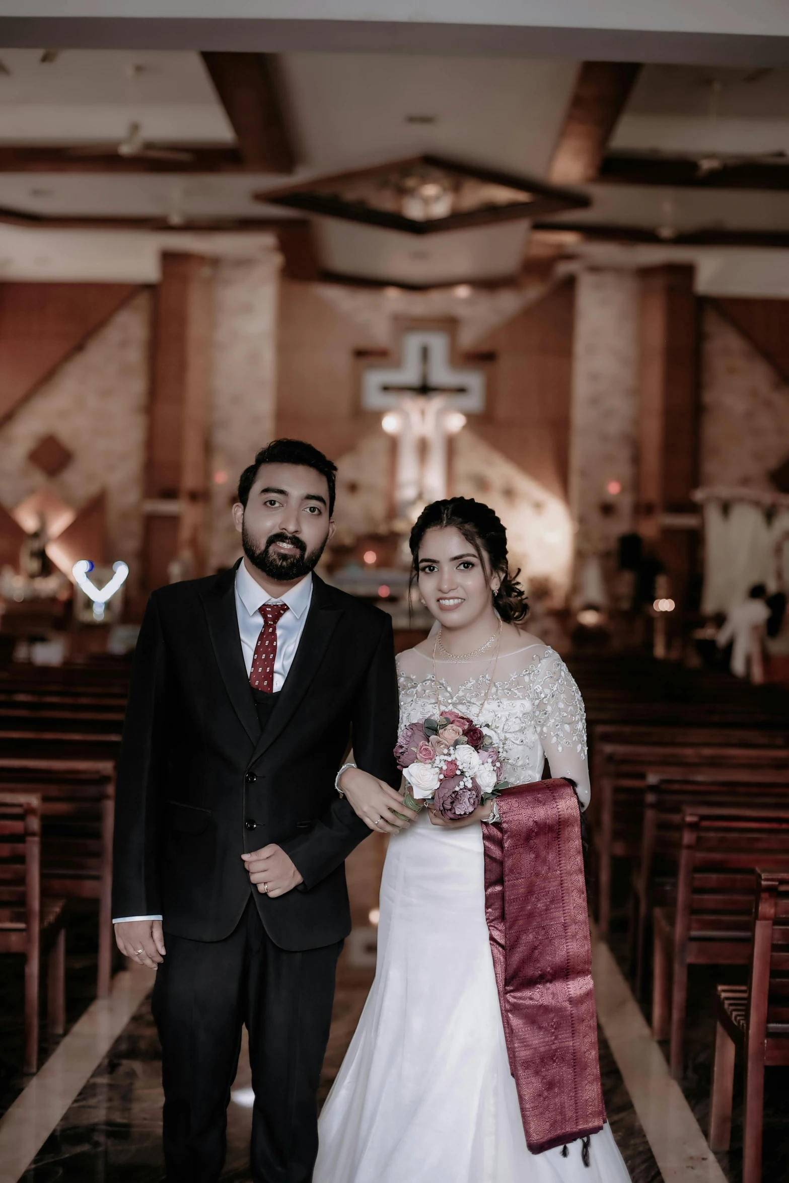 a man and woman in wedding clothes standing in front of pews