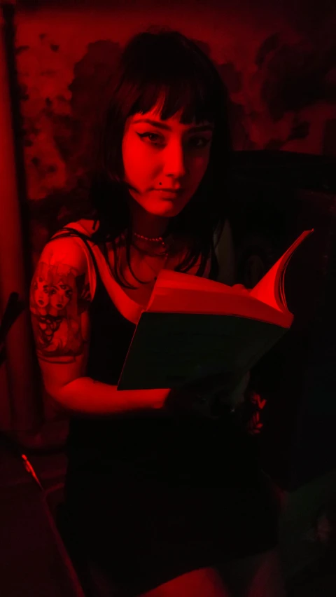 a woman with a tattoo holding a book in her hands