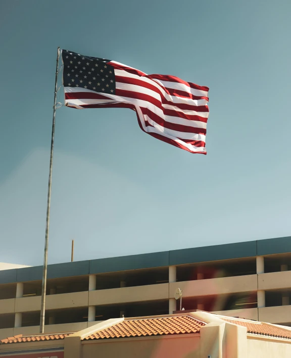 an american flag flying near a building on the side of a road