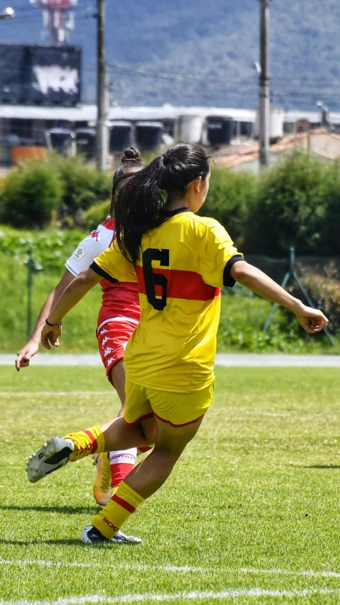 a woman kicking a soccer ball while standing on top of a field