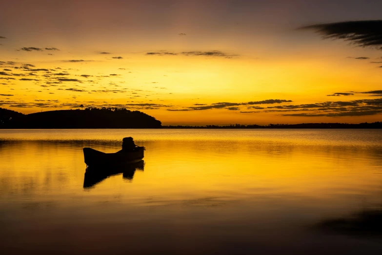 silhouette of a boat sitting in a calm lake