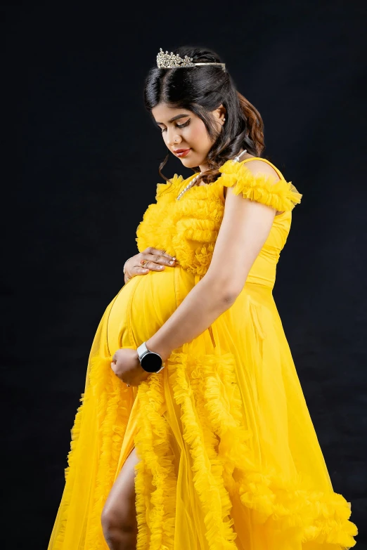 a pregnant woman in a yellow dress poses for a picture