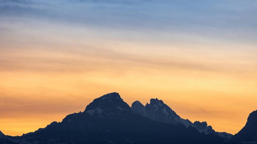 a plane flies across the sky in front of a large mountain